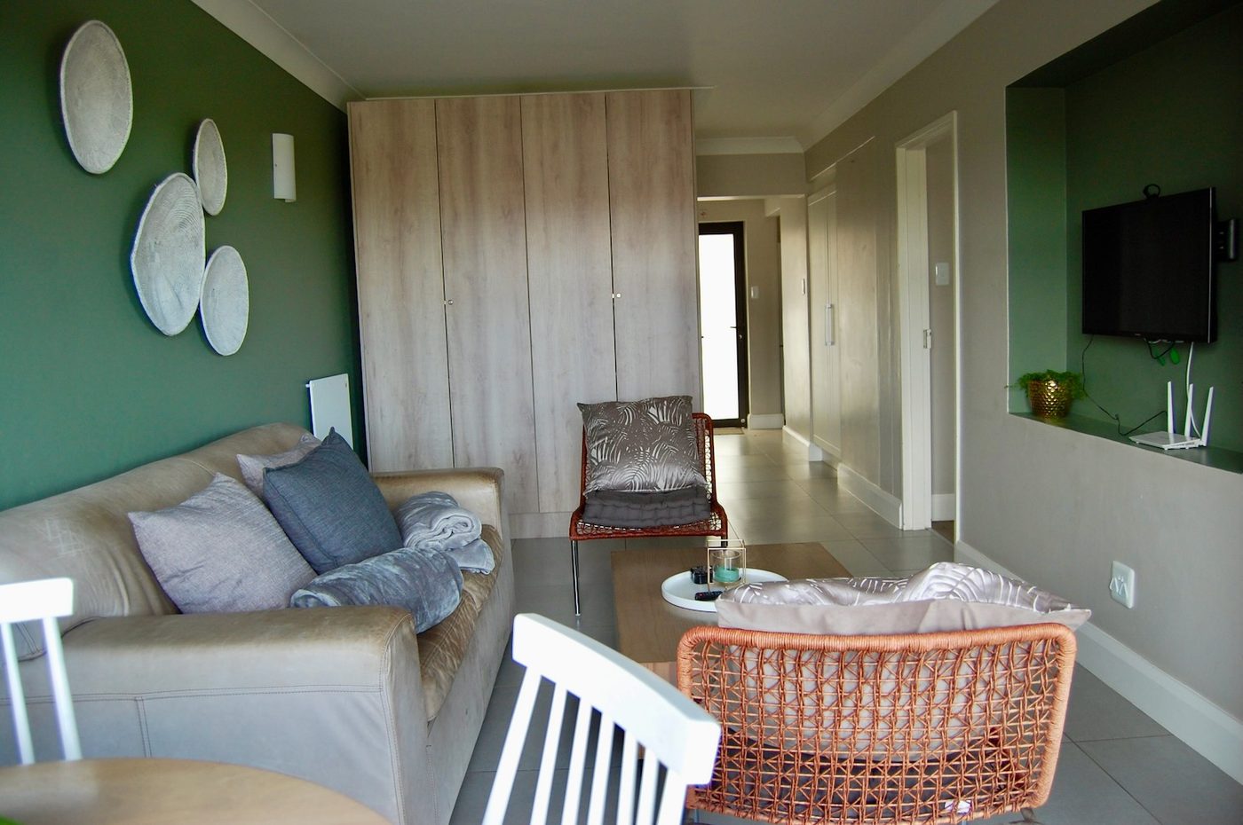 Open-plan lounge with a green feature wall at 70A, Castleton, Plettenberg Bay